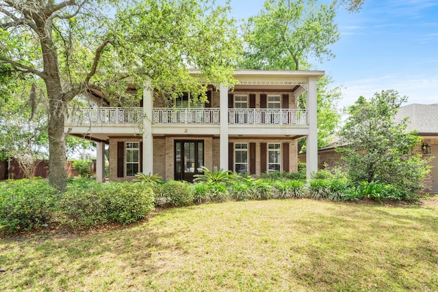 greek revival house featuring a front lawn, a balcony, and french doors