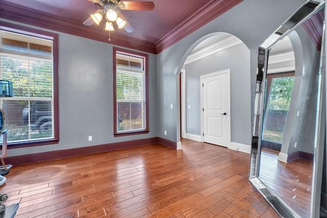 unfurnished room featuring plenty of natural light, hardwood / wood-style floors, ceiling fan, and ornamental molding