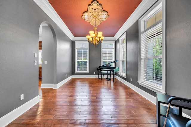 interior space featuring ornamental molding, a notable chandelier, plenty of natural light, and dark hardwood / wood-style flooring