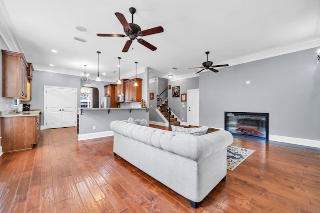 living room with hardwood / wood-style floors, ornamental molding, and ceiling fan