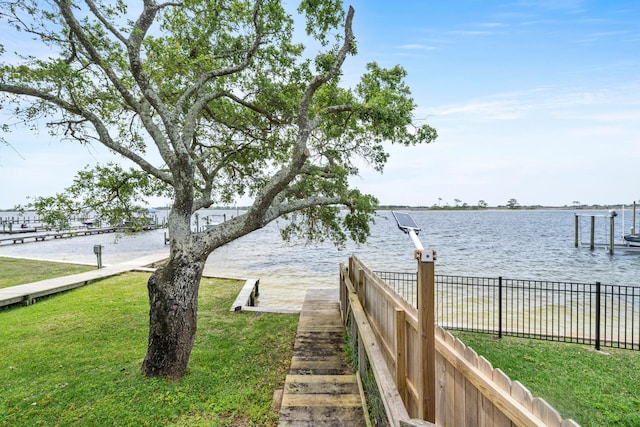 view of dock with a yard and a water view