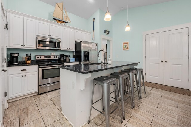 kitchen with pendant lighting, an island with sink, white cabinetry, and stainless steel appliances