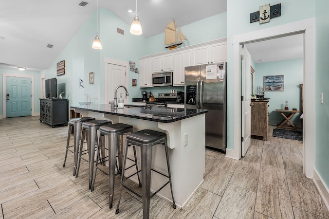 kitchen featuring appliances with stainless steel finishes, white cabinets, sink, pendant lighting, and a breakfast bar