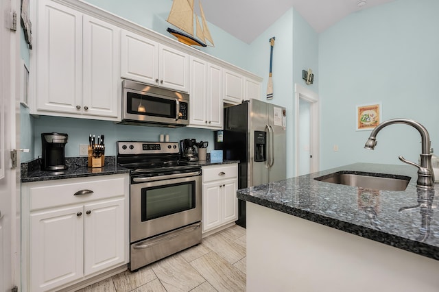 kitchen with appliances with stainless steel finishes, dark stone counters, white cabinetry, and sink