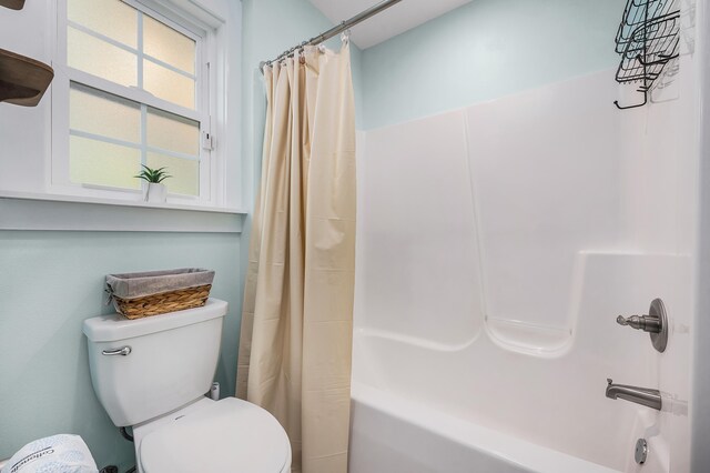 bathroom with a healthy amount of sunlight, toilet, and shower / bath combo with shower curtain