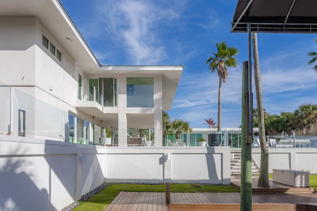 view of side of property with fence, a wooden deck, and stucco siding