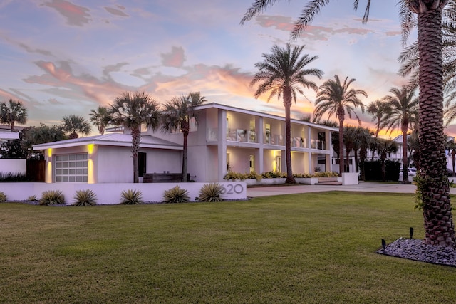 view of front facade featuring a garage, a lawn, driveway, and stucco siding