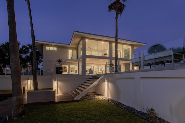 back of house at twilight with stucco siding and stairs