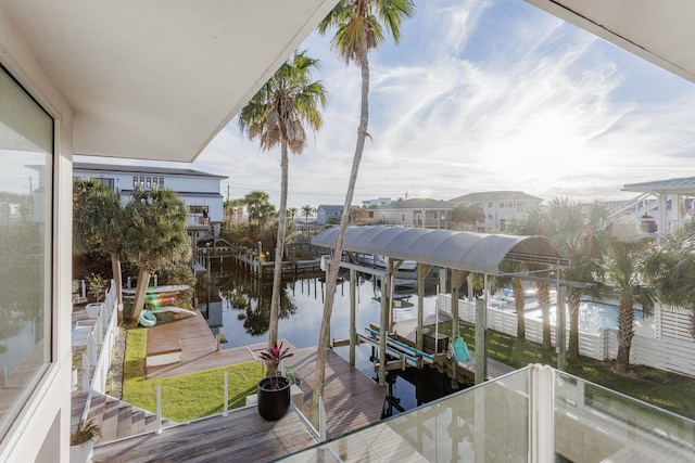 view of dock with a water view, boat lift, and a balcony