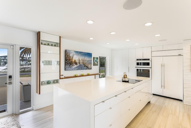 kitchen with paneled built in fridge, modern cabinets, a center island, black electric stovetop, and white cabinetry