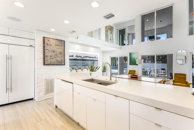 kitchen with white cabinetry, visible vents, light countertops, and a sink