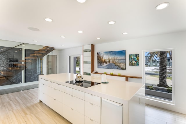 kitchen featuring a healthy amount of sunlight, modern cabinets, white cabinetry, and black electric cooktop