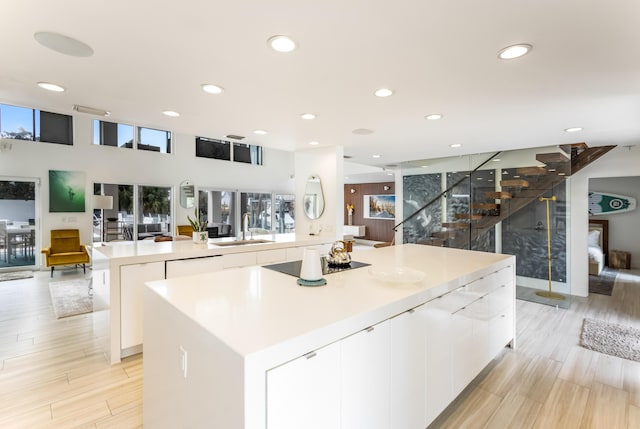 kitchen featuring a large island, white cabinets, a sink, modern cabinets, and black electric cooktop