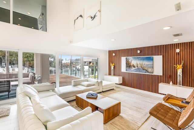 living area featuring an accent wall, a towering ceiling, visible vents, and recessed lighting