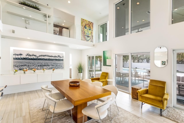 dining area with wood finished floors, a towering ceiling, and recessed lighting