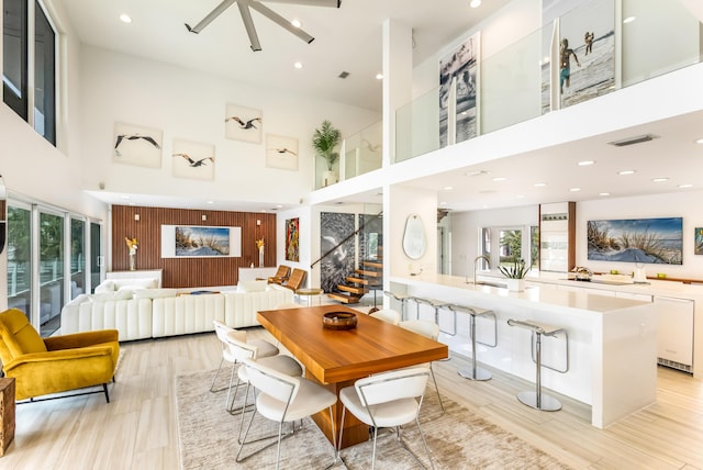 dining space with recessed lighting, a high ceiling, visible vents, light wood-style floors, and stairs