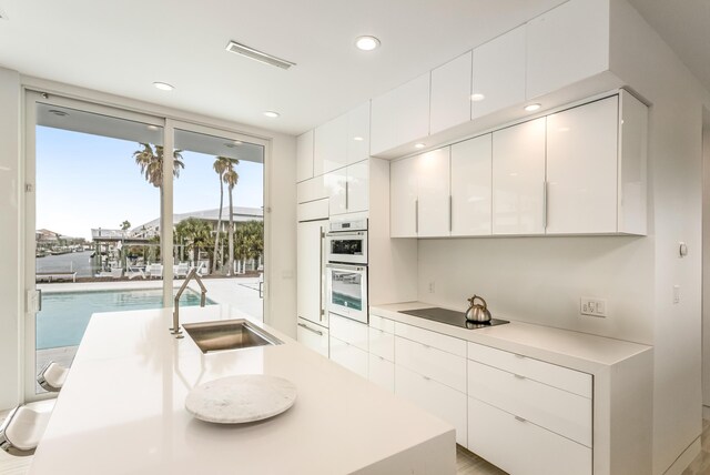 kitchen featuring visible vents, double oven, black electric cooktop, and white cabinetry