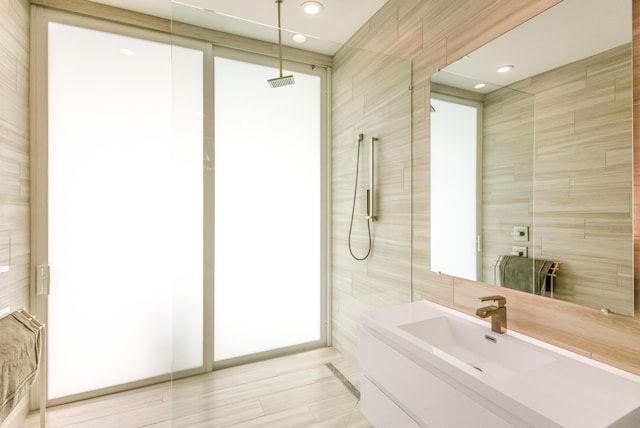 full bathroom featuring tile walls, recessed lighting, visible vents, a sink, and walk in shower