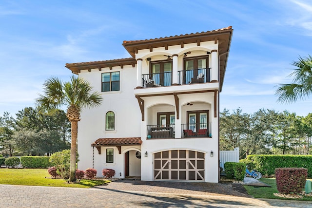 mediterranean / spanish-style home featuring a front lawn, french doors, a garage, and a balcony