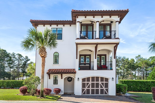 mediterranean / spanish-style house with french doors, a balcony, a garage, and a front yard