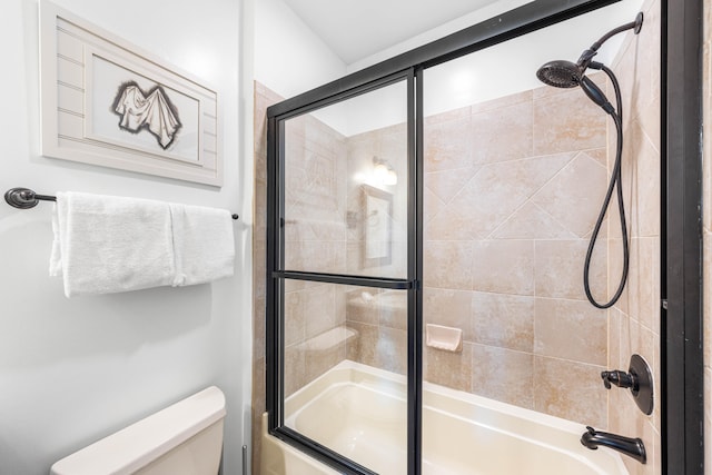 bathroom featuring toilet and bath / shower combo with glass door