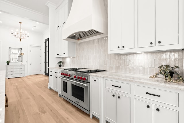 kitchen with range with two ovens, light hardwood / wood-style flooring, tasteful backsplash, custom exhaust hood, and white cabinetry