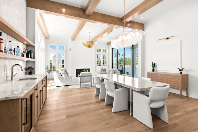 dining room with wine cooler, light hardwood / wood-style floors, beam ceiling, and sink