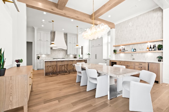 dining area featuring sink, light hardwood / wood-style flooring, and beam ceiling