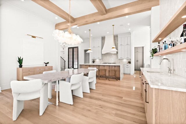 dining space with beamed ceiling, sink, and light wood-type flooring