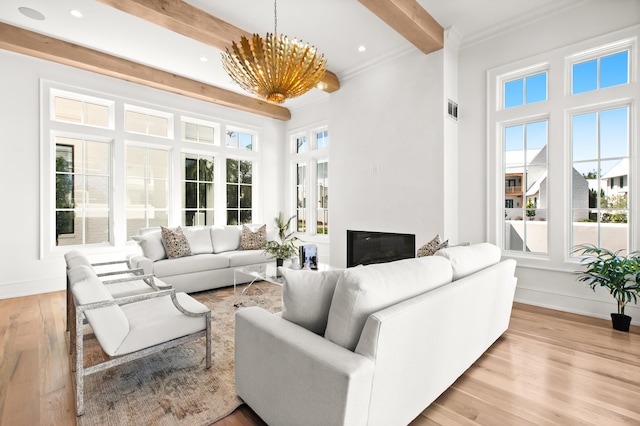 living room with ornamental molding, beam ceiling, light wood-type flooring, and an inviting chandelier