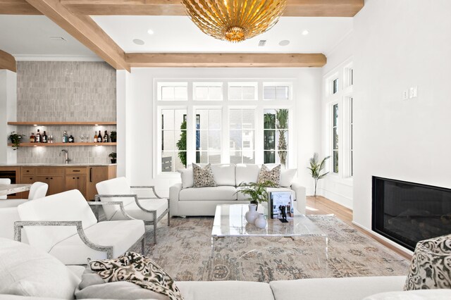 living room with light hardwood / wood-style flooring, beam ceiling, and sink