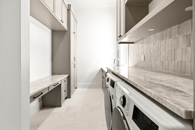 kitchen featuring white cabinets, light stone countertops, light tile flooring, and washer and clothes dryer