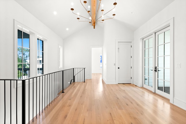 hallway with a chandelier, light hardwood / wood-style floors, french doors, and lofted ceiling