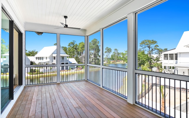 unfurnished sunroom featuring ceiling fan and a water view