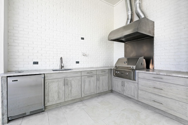 interior space with sink, refrigerator, wall chimney range hood, and light tile flooring