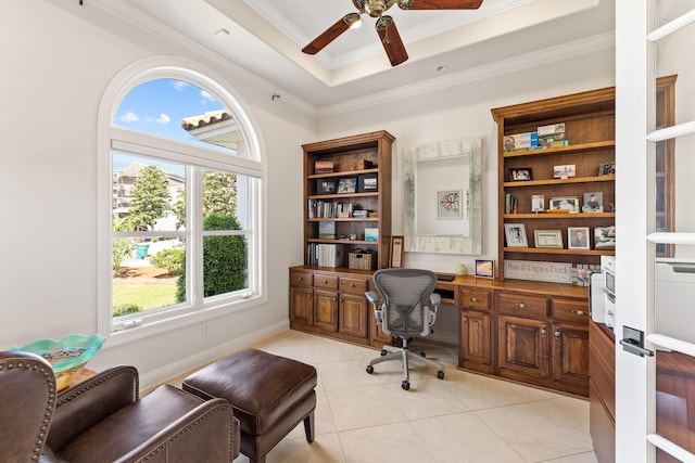 office area with ceiling fan, built in desk, a raised ceiling, light tile floors, and ornamental molding