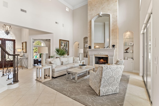 living room featuring built in shelves, a towering ceiling, a large fireplace, and light tile flooring