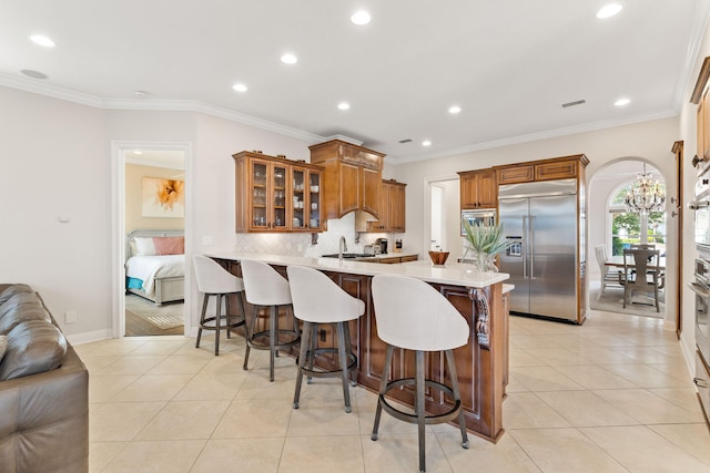 kitchen with kitchen peninsula, appliances with stainless steel finishes, crown molding, and a breakfast bar area