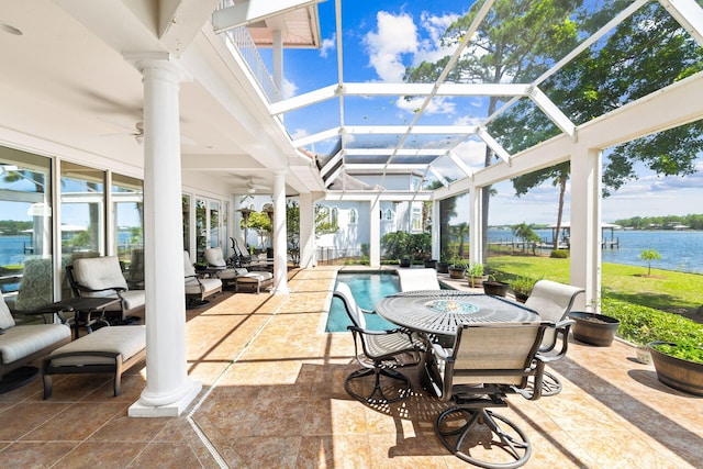 sunroom / solarium with decorative columns, ceiling fan, and a water view