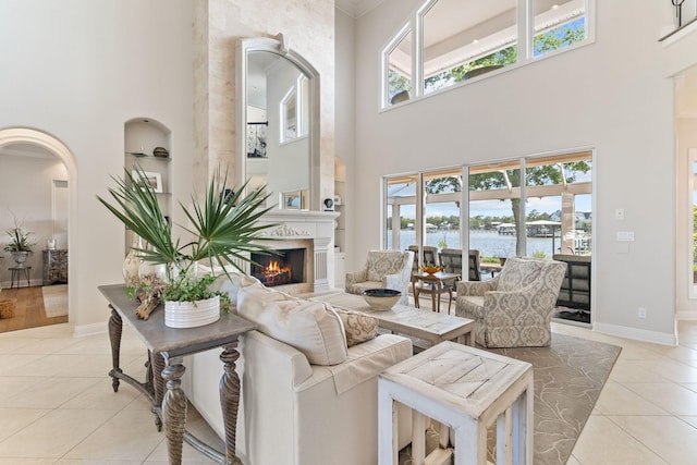 tiled living room featuring a water view, a towering ceiling, and a wealth of natural light