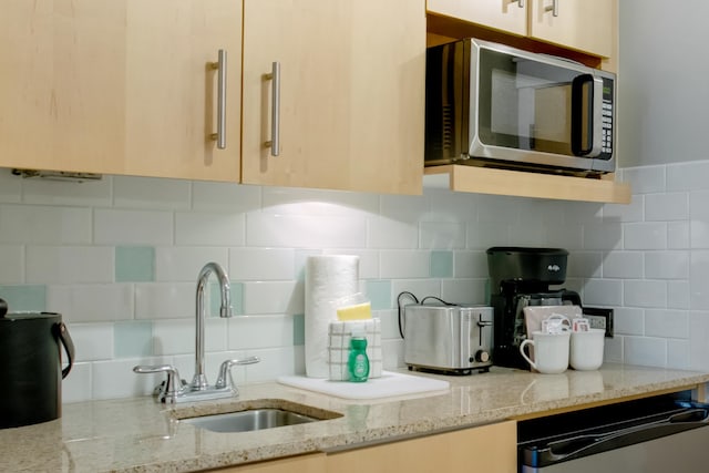 kitchen featuring tasteful backsplash, light stone countertops, sink, and dishwashing machine