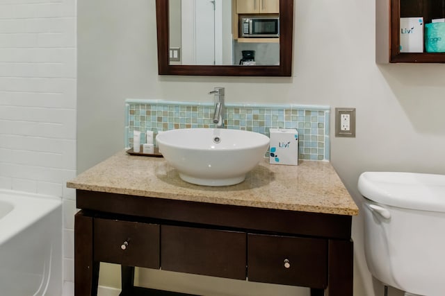 bathroom with tasteful backsplash, toilet, and vanity