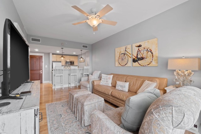 living room featuring ceiling fan and light wood-type flooring