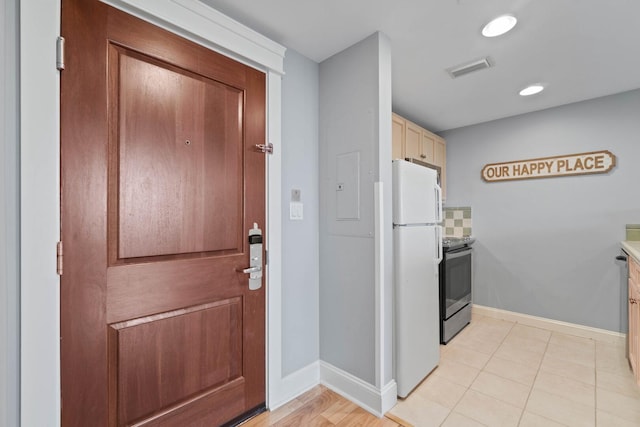 interior space featuring white refrigerator, stainless steel range with electric cooktop, and light tile floors