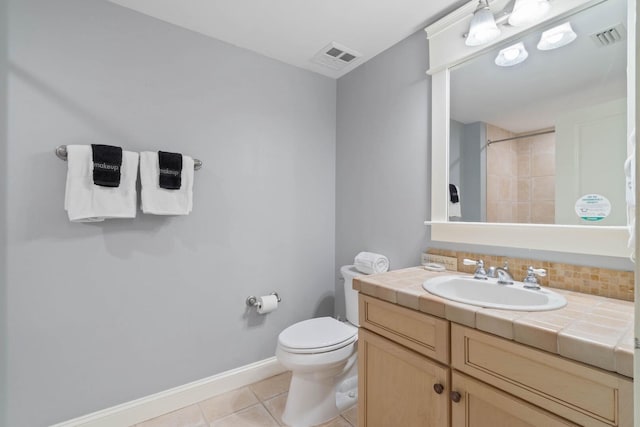 bathroom featuring tile flooring, vanity, and toilet