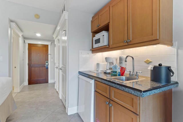 kitchen with sink, white appliances, tasteful backsplash, and light tile floors