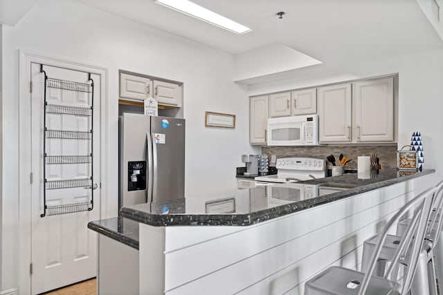 kitchen with kitchen peninsula, backsplash, white appliances, light tile patterned floors, and dark stone countertops