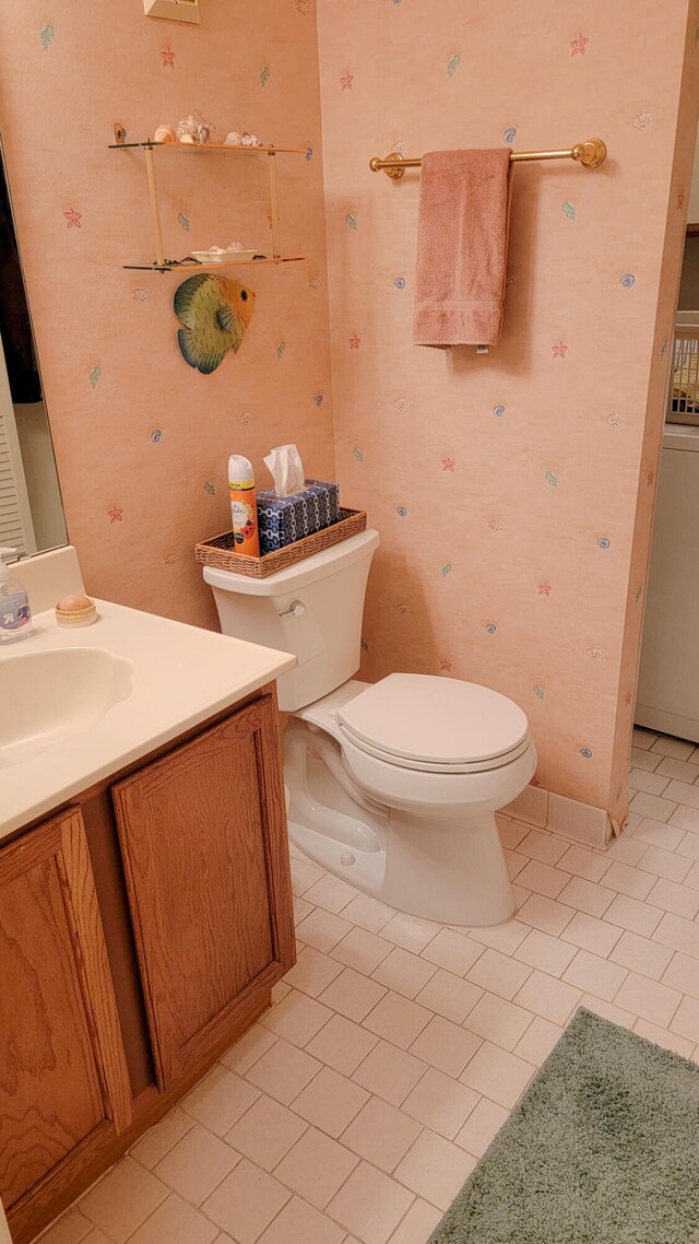 bathroom with washer / clothes dryer, vanity, tile floors, and toilet