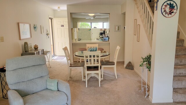 carpeted dining room with ceiling fan