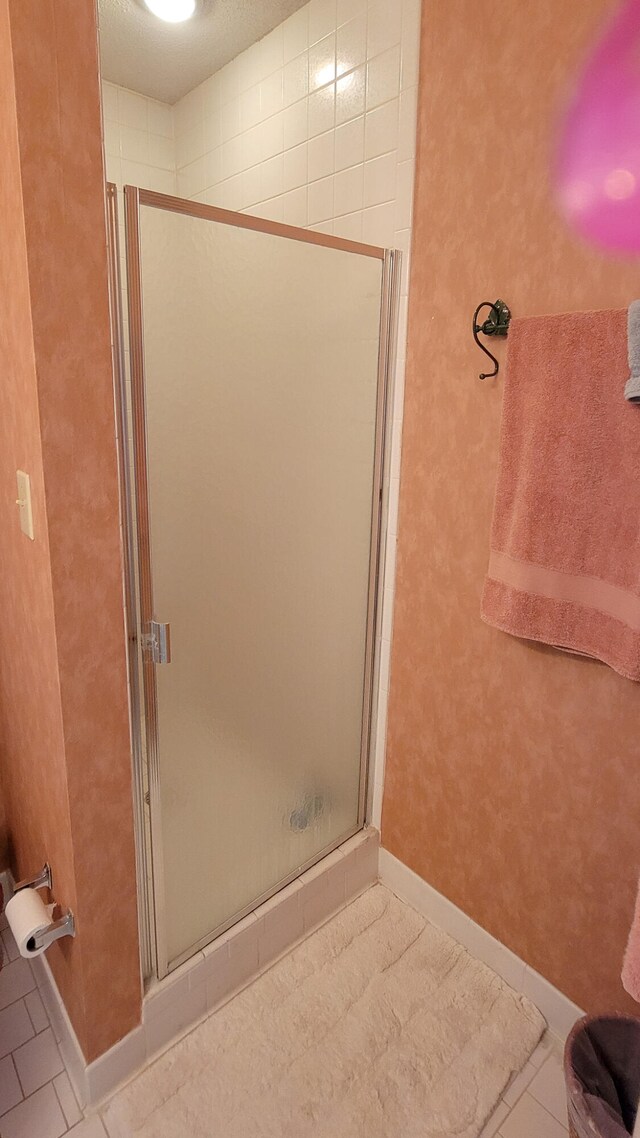 bathroom featuring an enclosed shower and tile flooring